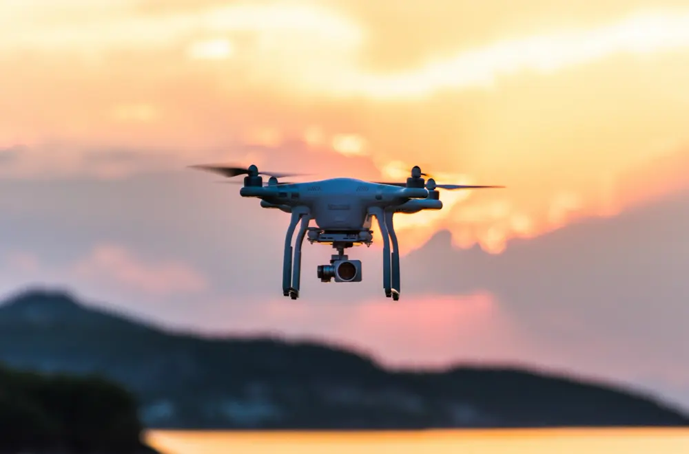 Camera drone flying against a sunset sky