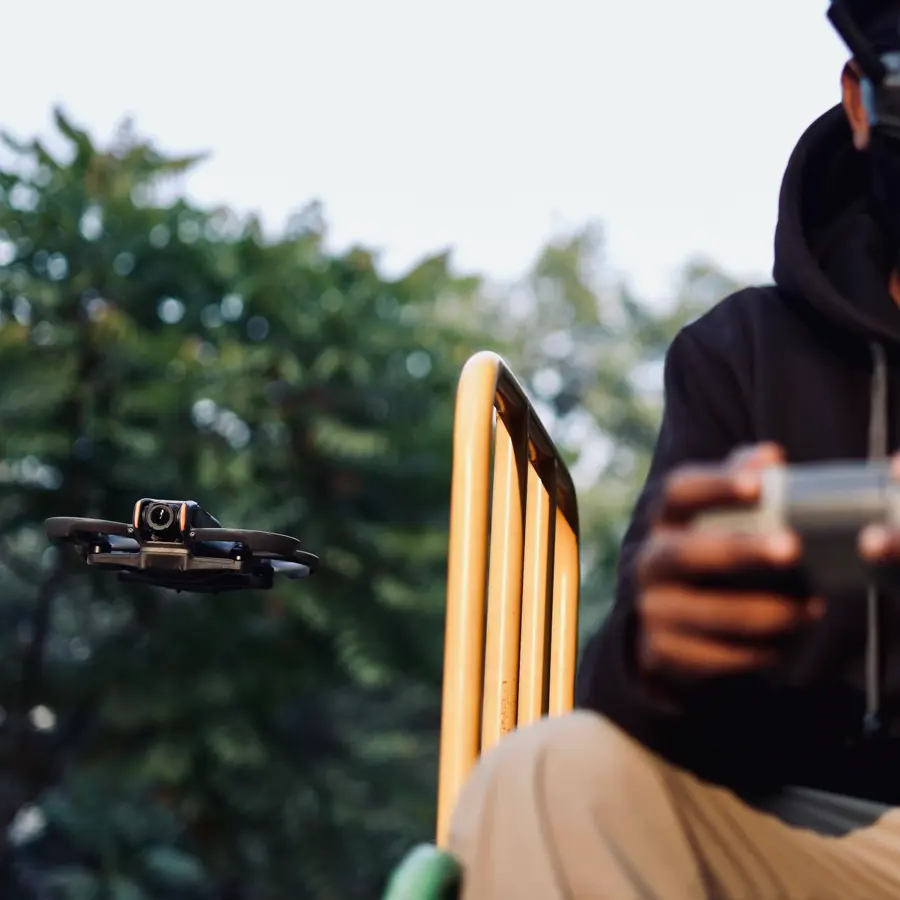 FPV pilot holding the controller while a small drone hovers nearby