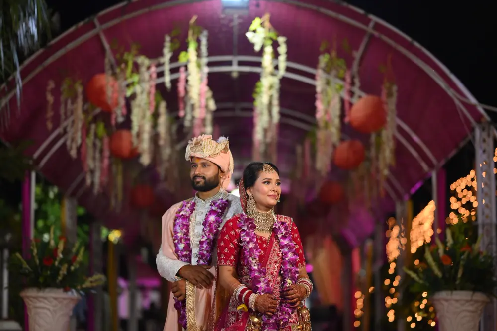 Newly married couple under a flower-decorated mandap at night